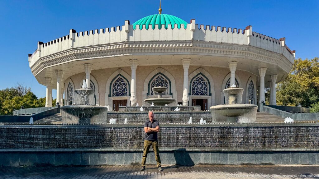 Man in dark shirt centered below turquoise dome.