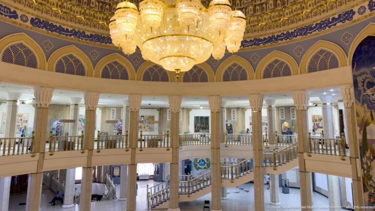 Chandelier above columns, upper gallery, stairs, and visitors.