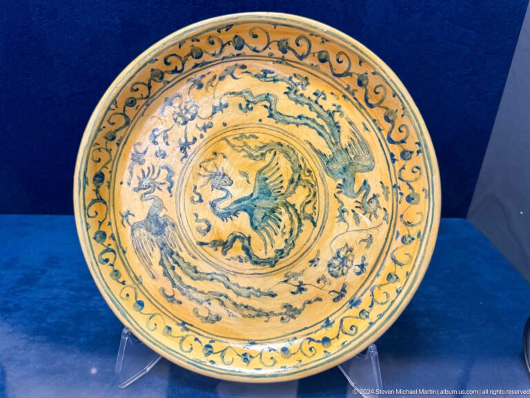 Yellow dish with blue-green bird medallion and curling border.