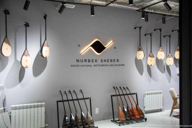 Interior of a decorative lighting store in Almaty, Kazakhstan, with multiple modern pendant lamps hanging from the ceiling.