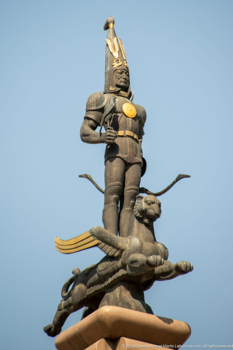 Side view of the Golden Warrior statue standing atop a horizontally extended winged leopard.