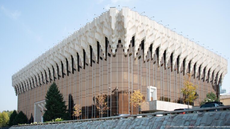 Wide oblique view of the Palace of the Republic in Almaty, Kazakhstan, showing its long façade and surrounding sloped landscaping.