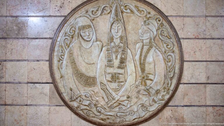 Circular stone relief medallion depicting traditional musicians carved in shallow detail on an exterior surface.