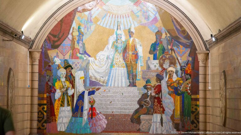 Close view of a metro mosaic showing Kazakh rulers, warriors, and cultural figures in a stepped composition with bright radiating light at the top.