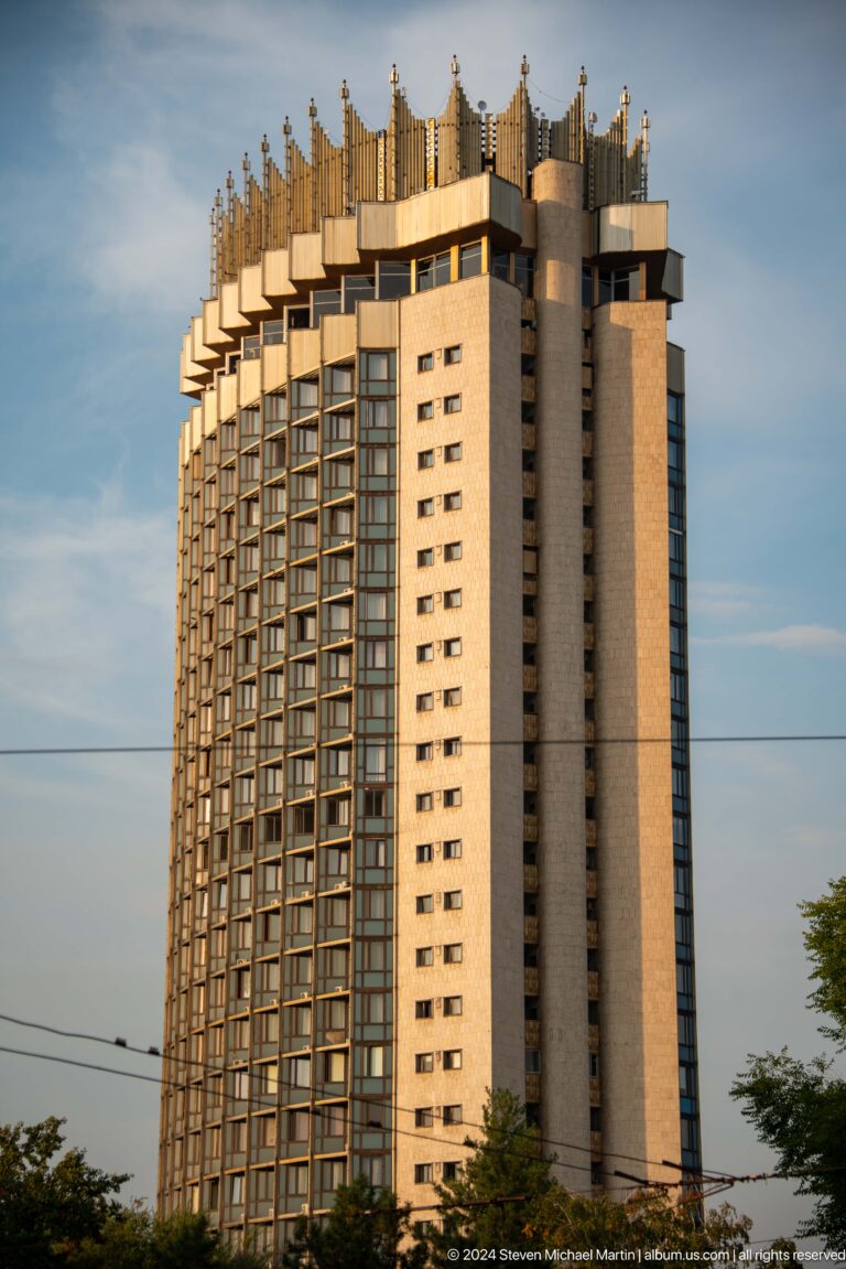 Tall cylindrical tower of Hotel Kazakhstan in Almaty with a decorative crown-shaped roofline above a grid of windows.