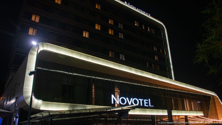Night view of Novotel Almaty City Center with its facade illuminated against the dark sky.