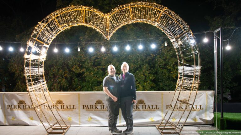 Two men stand together at night inside an illuminated heart-shaped sculpture at the Park Hotel in Almaty, Kazakhstan.