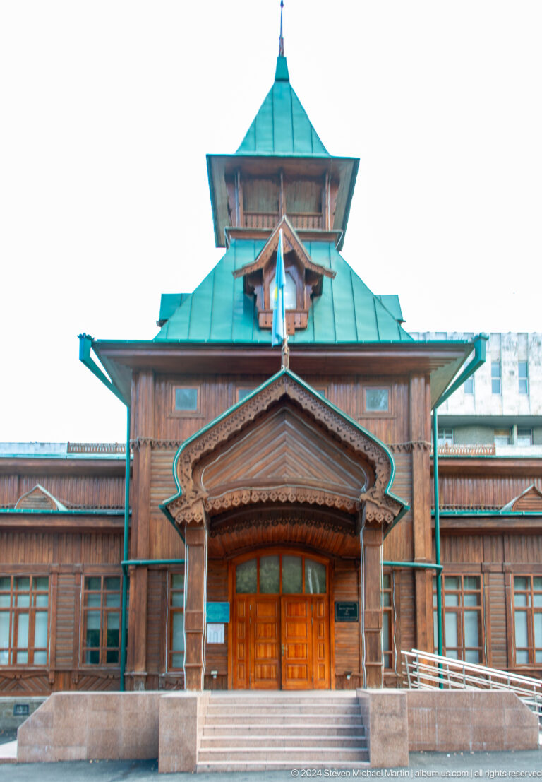 Ornate wooden gable with a turquoise roof on the facade of Ascension Cathedral in Almaty, Kazakhstan.