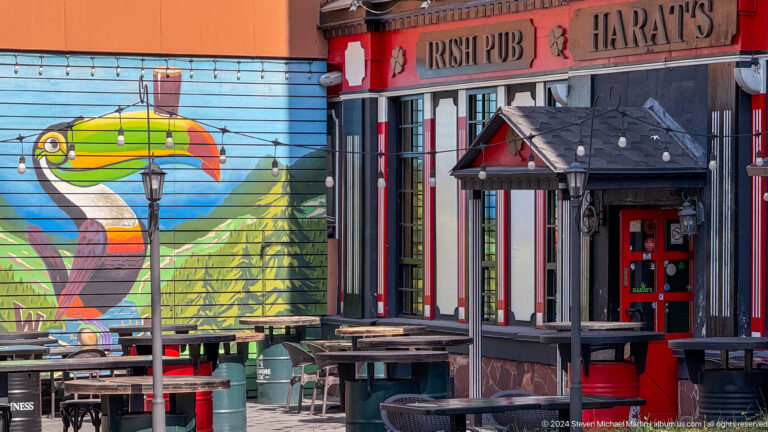Exterior of an Irish pub in Almaty with a large toucan mural painted on the wall facing the street.