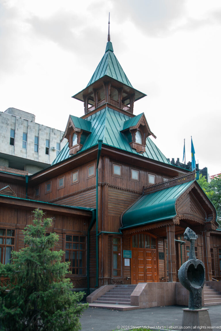 Side view of the wooden Ascension Cathedral in Almaty with green roofs and ornate detailing.