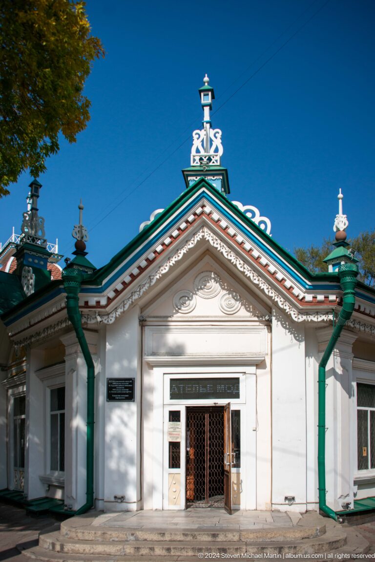 White and green ornamental entrance of a historic-style civic or cultural building in Almaty, Kazakhstan.