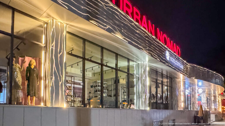 Illuminated Iran Nomad shop exterior at night in Almaty, Kazakhstan.