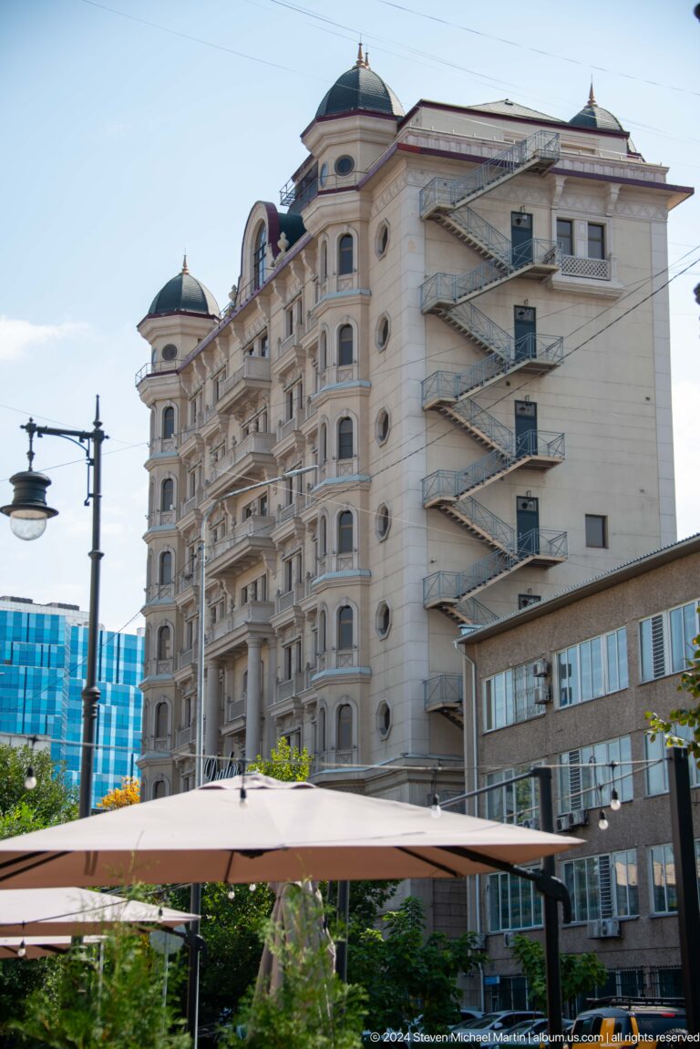 Facade of a weathered Soviet-era apartment building in Almaty with external staircases and balconies.