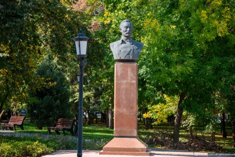 Commemorative bust on a tall pedestal in a leafy park in Almaty, Kazakhstan.