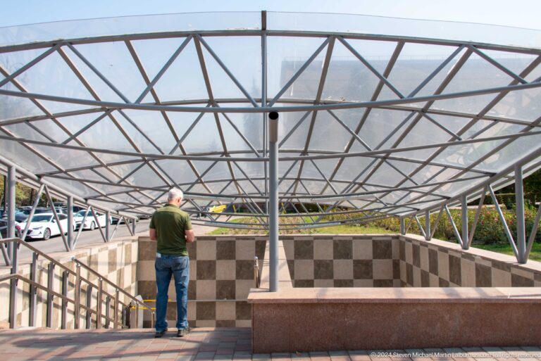 Open-air rooftop terrace in Almaty covered by a lightweight metal truss canopy.