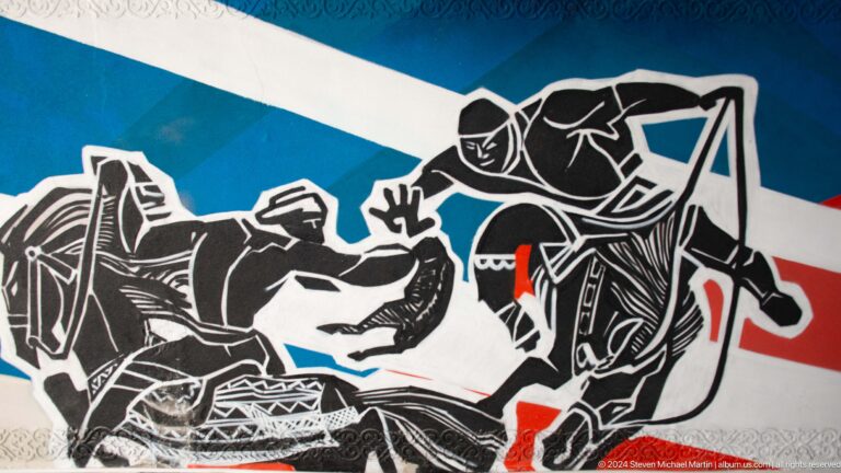 Black, white, and red mural depicting mounted warriors in battle in Almaty, Kazakhstan.