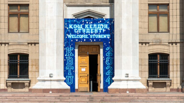 Front view of an Almaty institution entrance with a blue decorated sign reading Welcome Student above the doorway.
