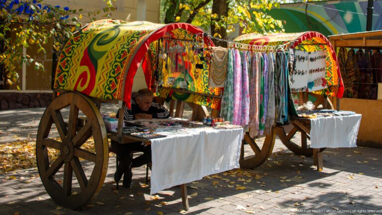Ornamental Kazakh heritage cart decorated with patterned textiles and carved details in a cultural display setting.