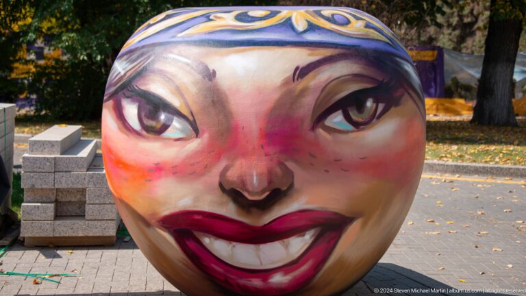 Close-up of a painted spherical public art piece in Almaty, Kazakhstan, showing a large stylized female face.
