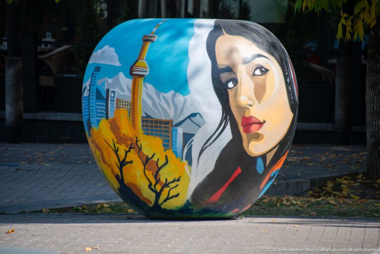 Painted spherical public artwork in Almaty, Kazakhstan, showing a woman’s portrait set within a mountain landscape.