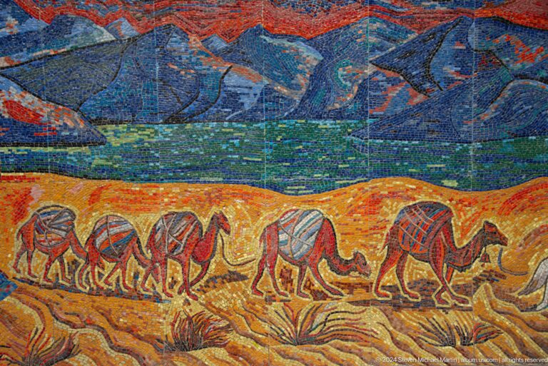 Mosaic frieze of running animals set against stylized mountains in Almaty, Kazakhstan.