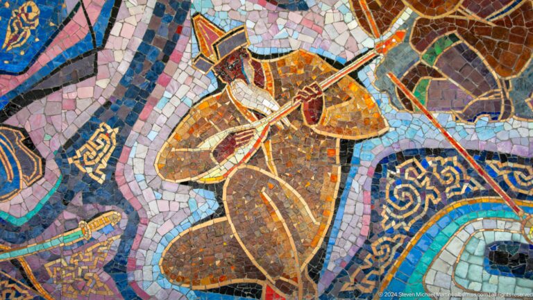 Detail of a figurative mosaic panel showing a seated person holding a vessel, composed of small colored tiles.