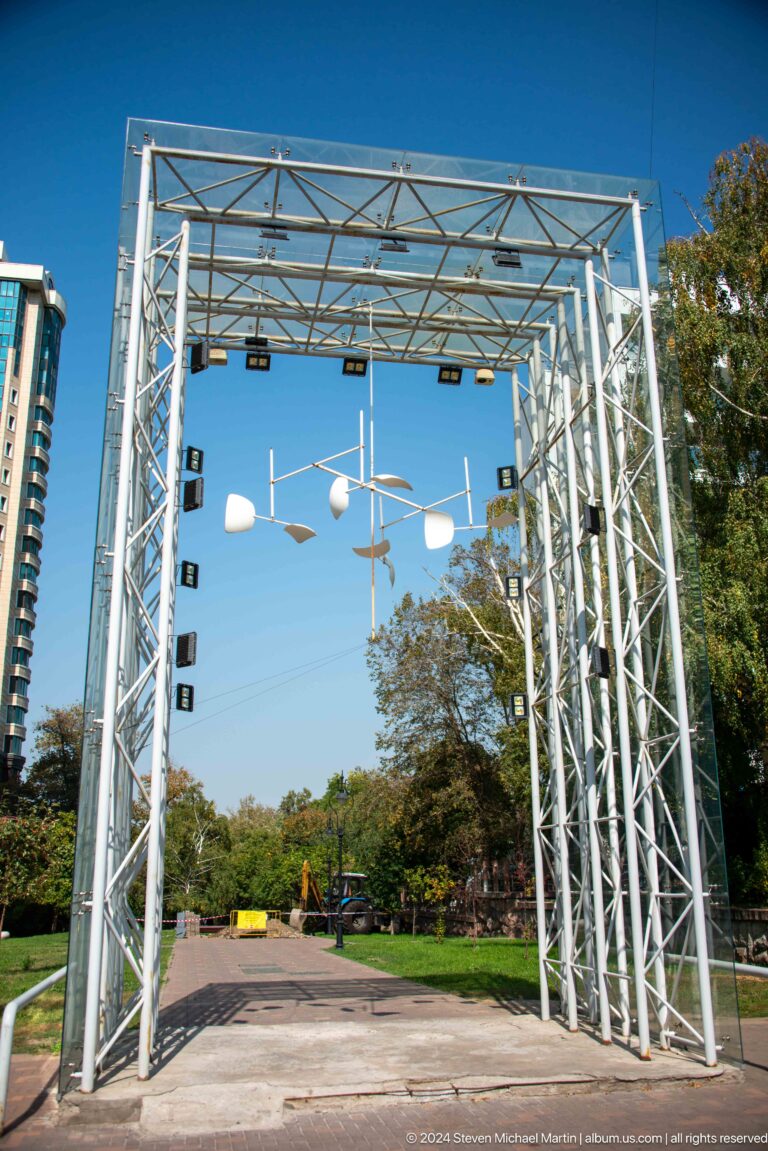 Metal truss structure with hanging stage lights silhouetted against a clear blue sky.