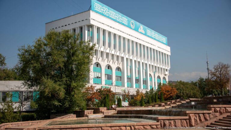 Large turquoise-trimmed institutional building in Almaty, Kazakhstan, seen behind stepped fountain terraces.