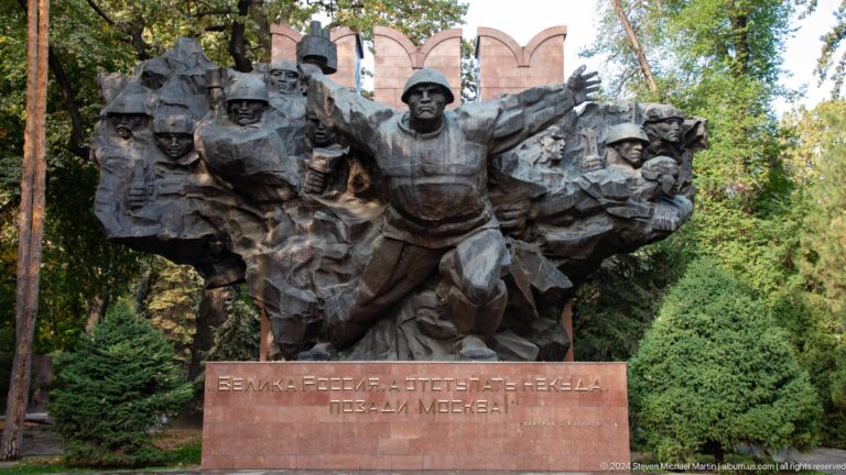 Close frontal view of central heroic Soviet-era bronze soldier figures at a war memorial sculpture in Almaty, Kazakhstan.