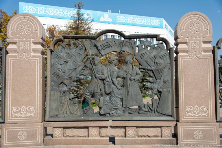 Bronze relief panel filled with narrative figures in a public art setting in Almaty, Kazakhstan.