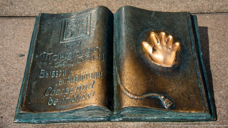Open bronze book sculpture with inscription and a handprint impression in Almaty, Kazakhstan.