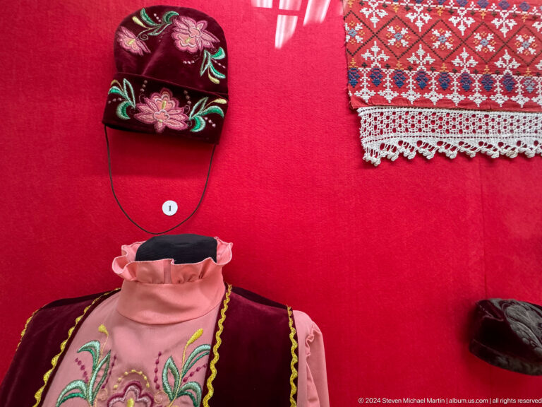 Pink blouse and embroidered textiles mounted against a red exhibition backing in the Central State Museum of Kazakhstan in Almaty.