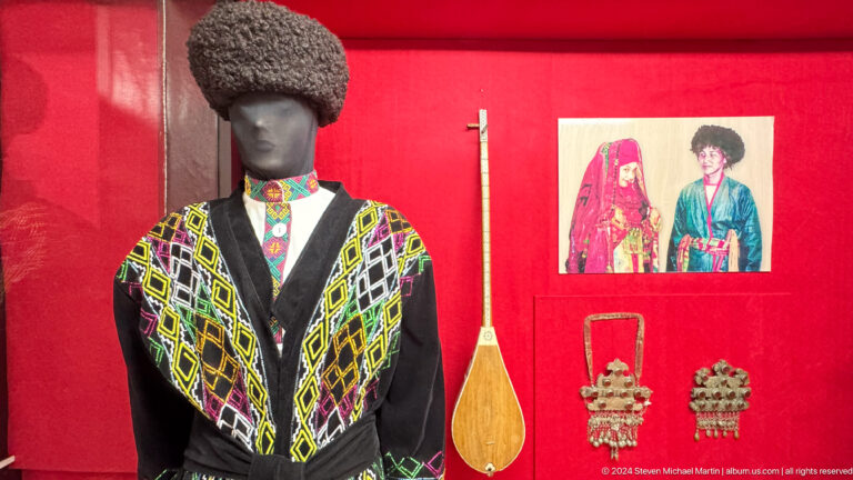 Mannequin in a patterned green and black traditional garment beside a long-necked lute in the Central State Museum of Kazakhstan in Almaty.