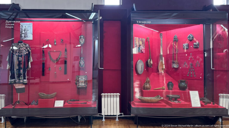 Medium view of two adjoining red ethnographic display cases in the Central State Museum of Kazakhstan in Almaty.