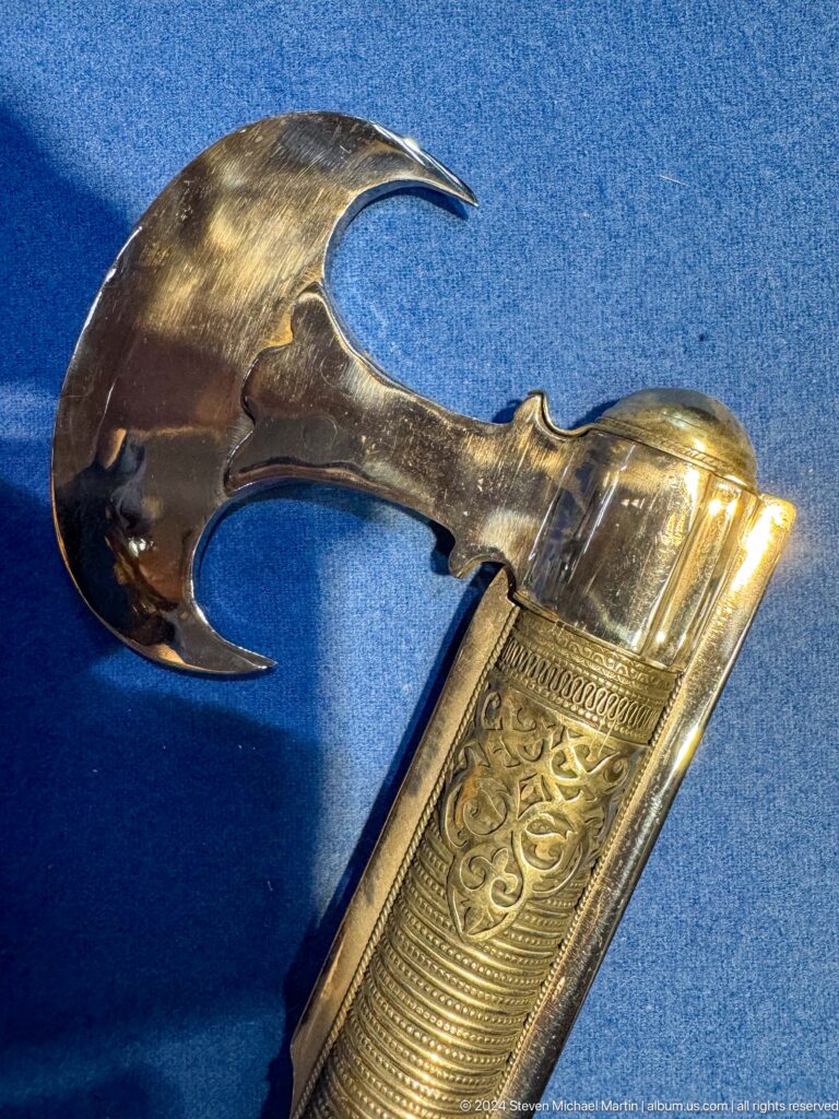 Close-up of a gold-decorated historic pistol grip and trigger guard in a display at the Central State Museum of Kazakhstan in Almaty.