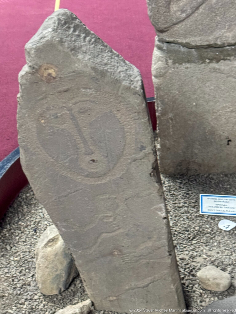Medium view of a rounded gray carved stone head on display at the Central State Museum of Kazakhstan in Almaty.