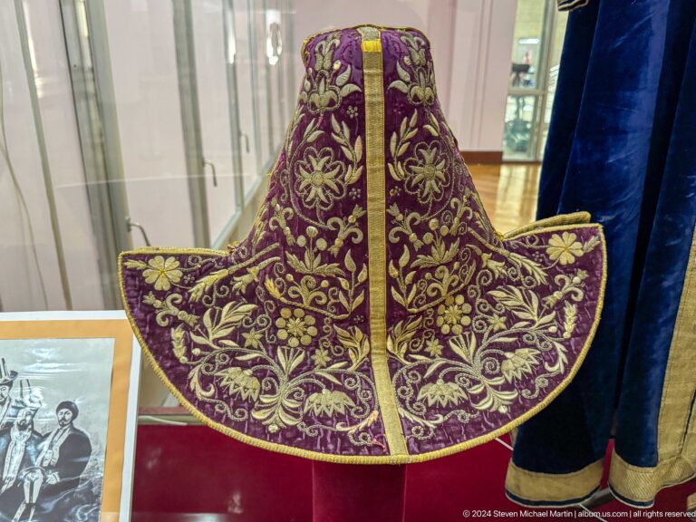 Purple velvet ceremonial robe with gold embroidery displayed against a red backing at the Central State Museum in Almaty, Kazakhstan.