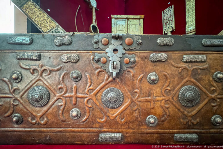 Close-up of a leather chest studded with reflective metal ornaments, part of the Central State Museum collection in Almaty, Kazakhstan.