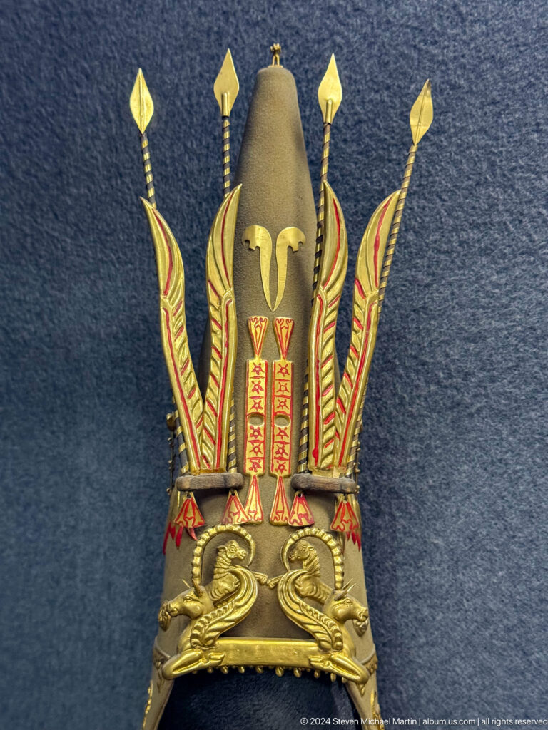Close-up of a gold-colored helmet crest with stylized animal ornaments on display in the Central State Museum in Almaty, Kazakhstan.