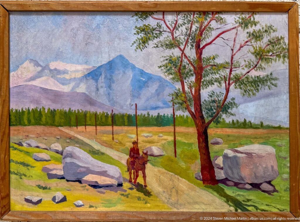 Kazakh mountain landscape painting showing distant peaks, trees, a grazing animal, and a standing figure, documented in the Central State Museum of Kazakhstan in Almaty.