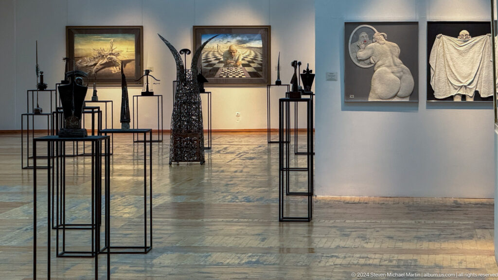 Wide modern gallery with sparse sculpture displays.