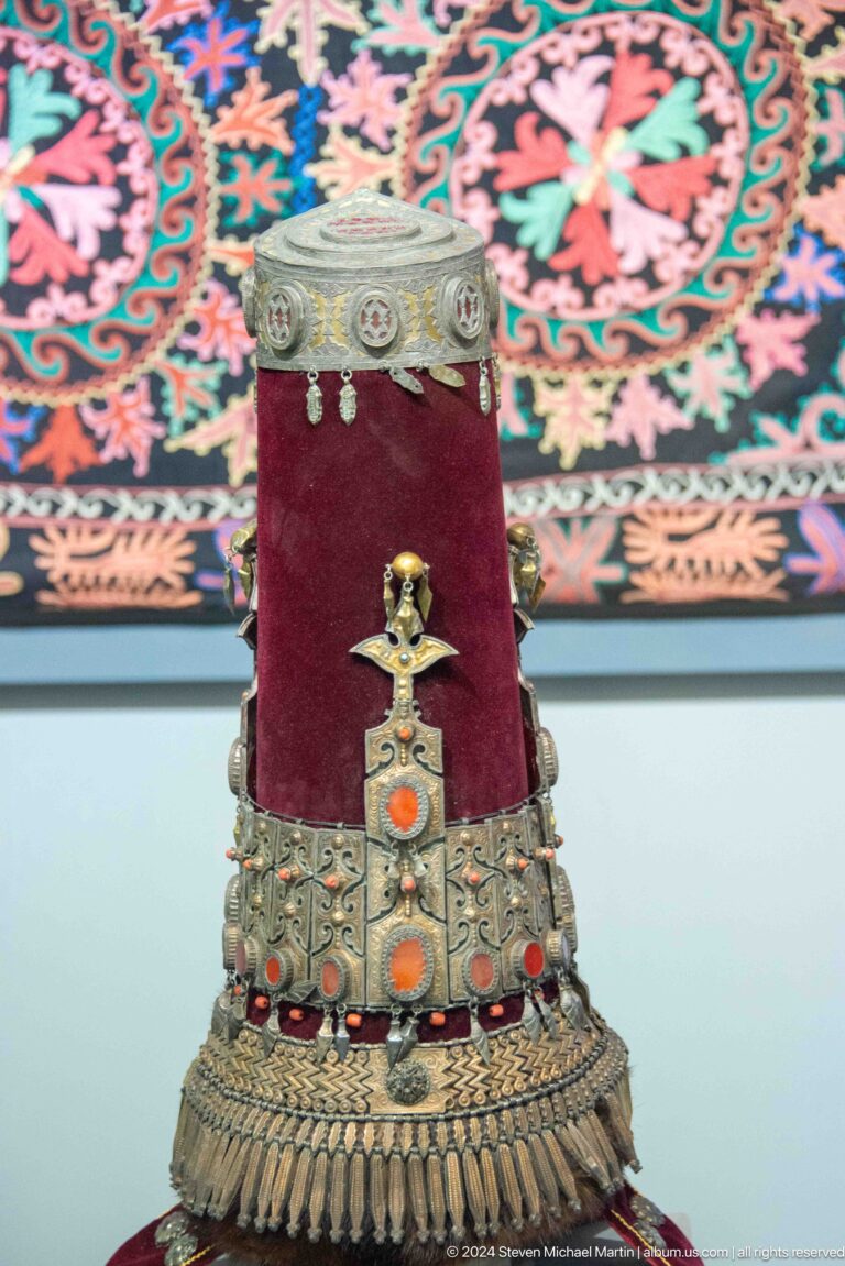 Ceremonial pendant displayed on burgundy textile.