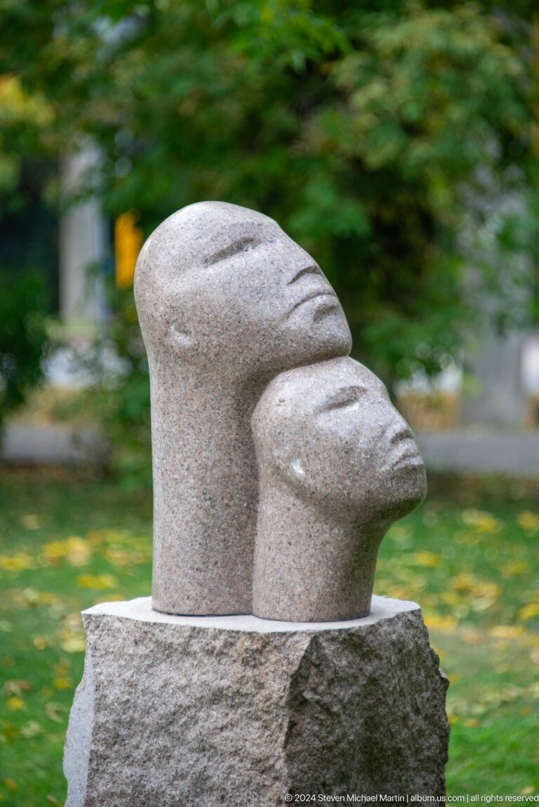 Profile of carved pale stone head outdoors.