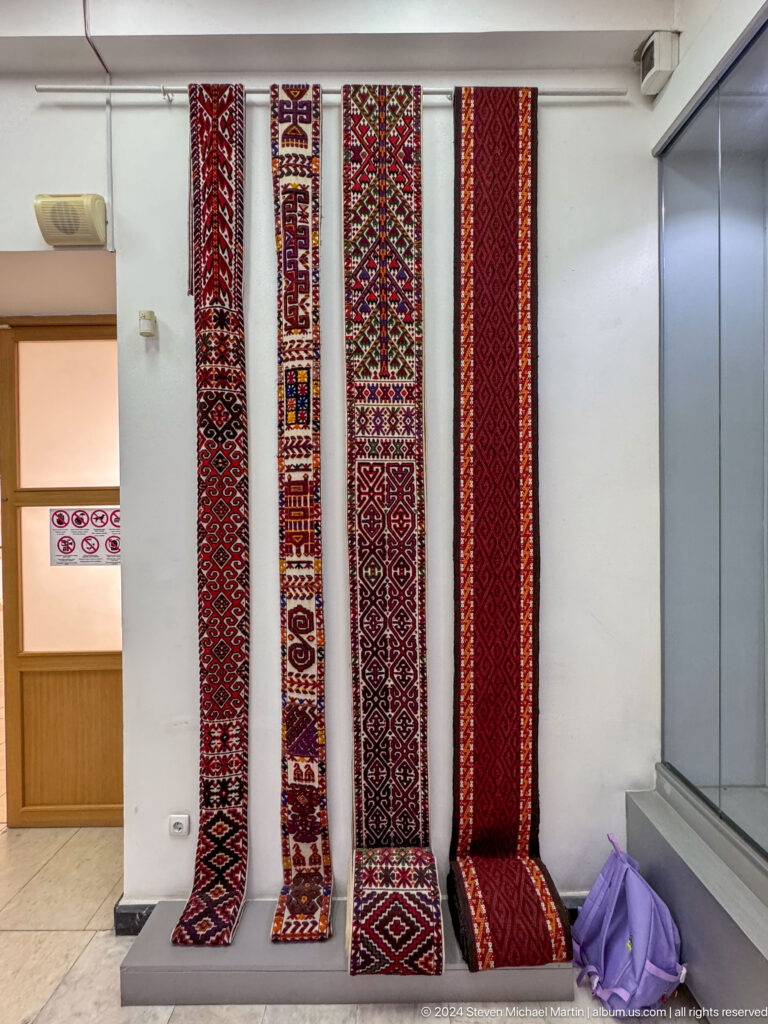 Vertical woven bands displayed behind glass.