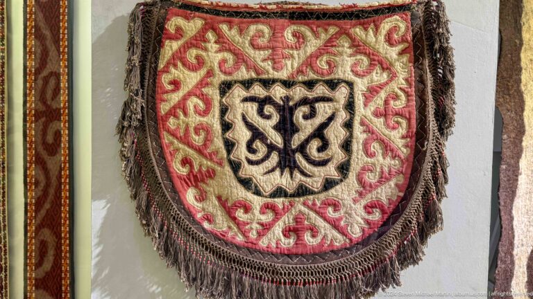Round fringed red textile with central motif.