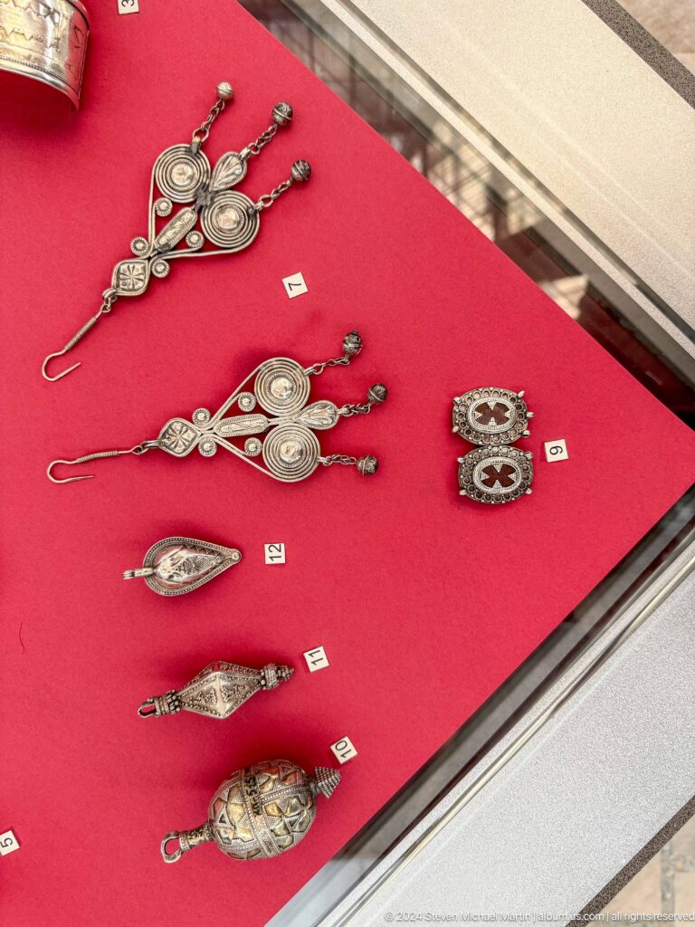 Silver ornaments arranged on red display.