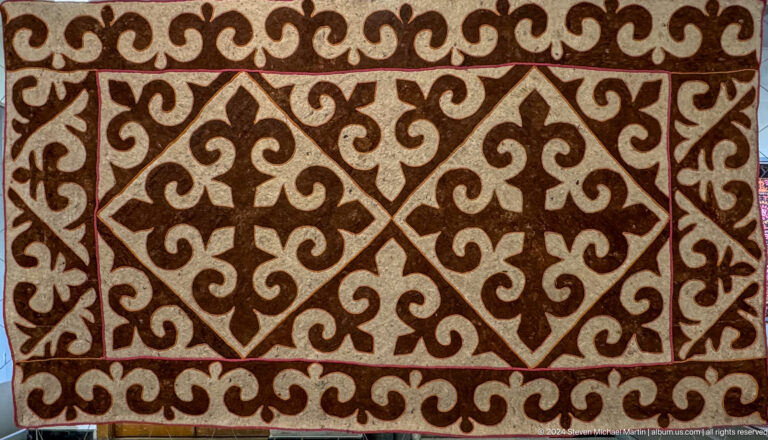 Brown and cream textile with scrolling pattern.