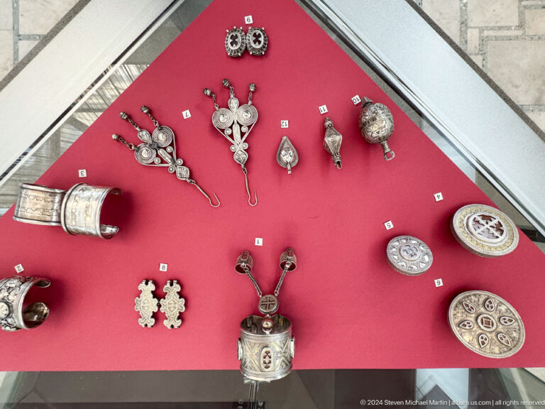 Assorted pendants and amulets on red display.