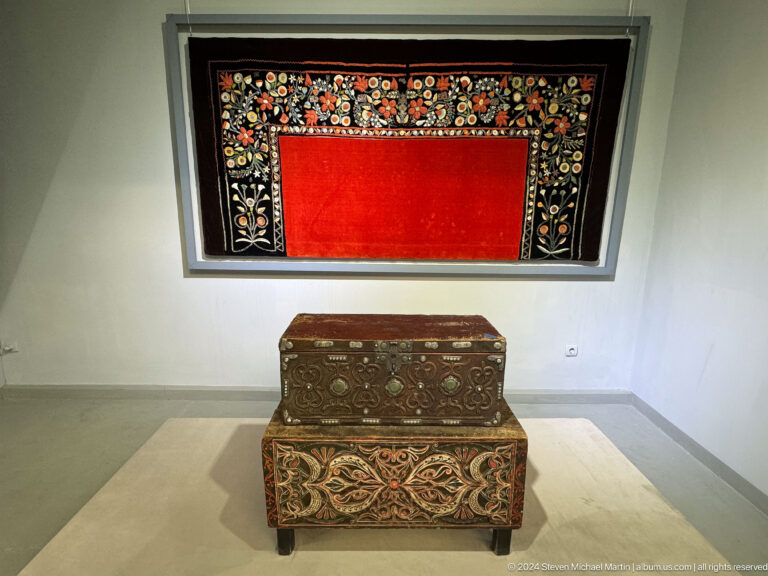 Painted chest beneath red wall textile.