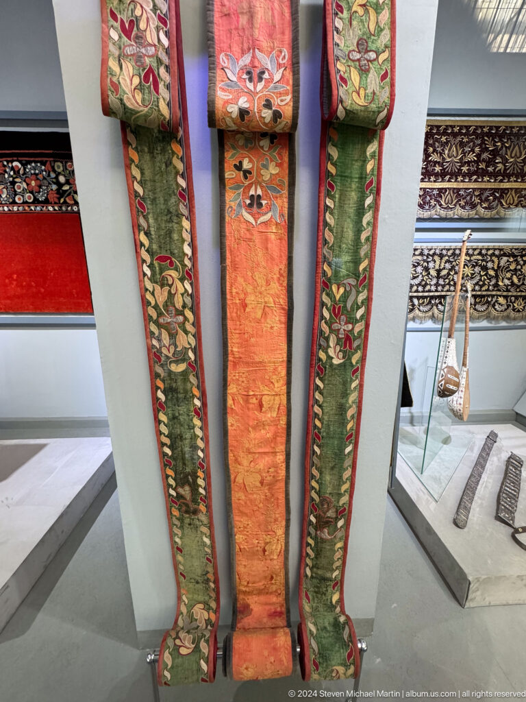 Three long embroidered textile straps.